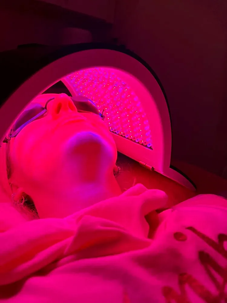 Person using LED light therapy facial treatment.