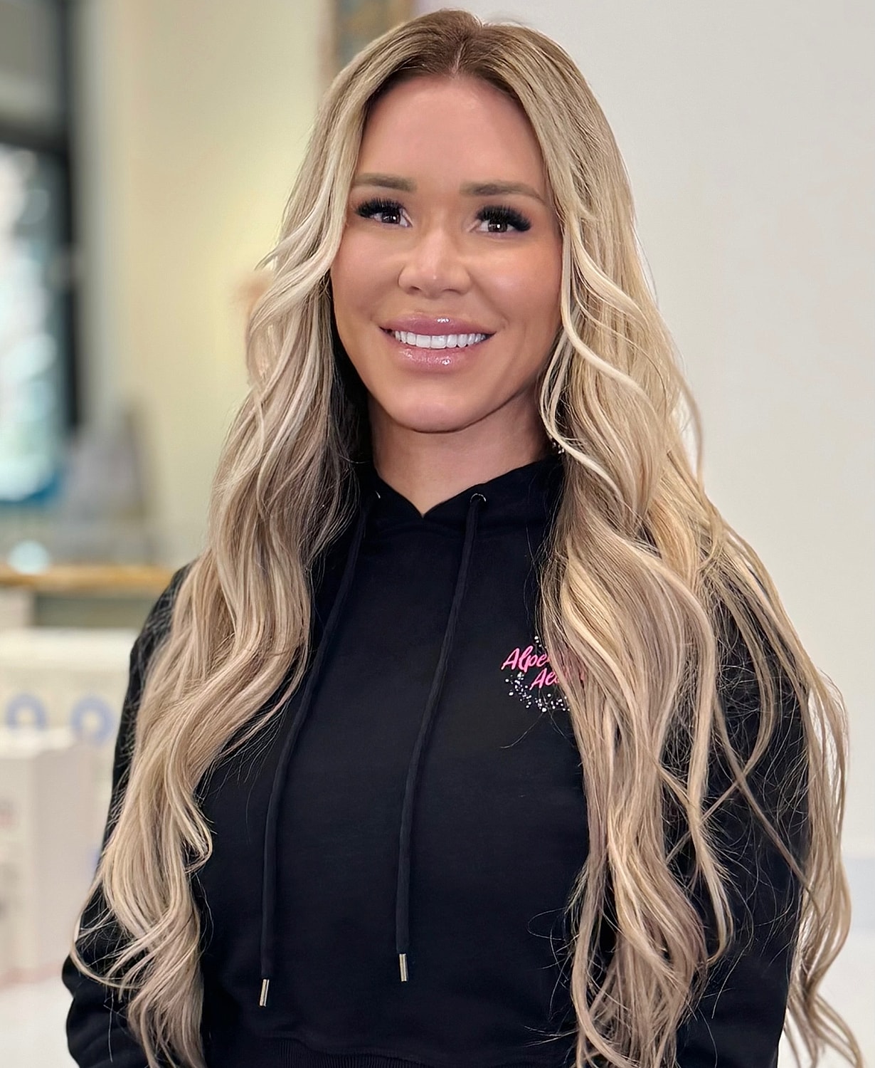 Smiling woman with long blonde hair indoors.