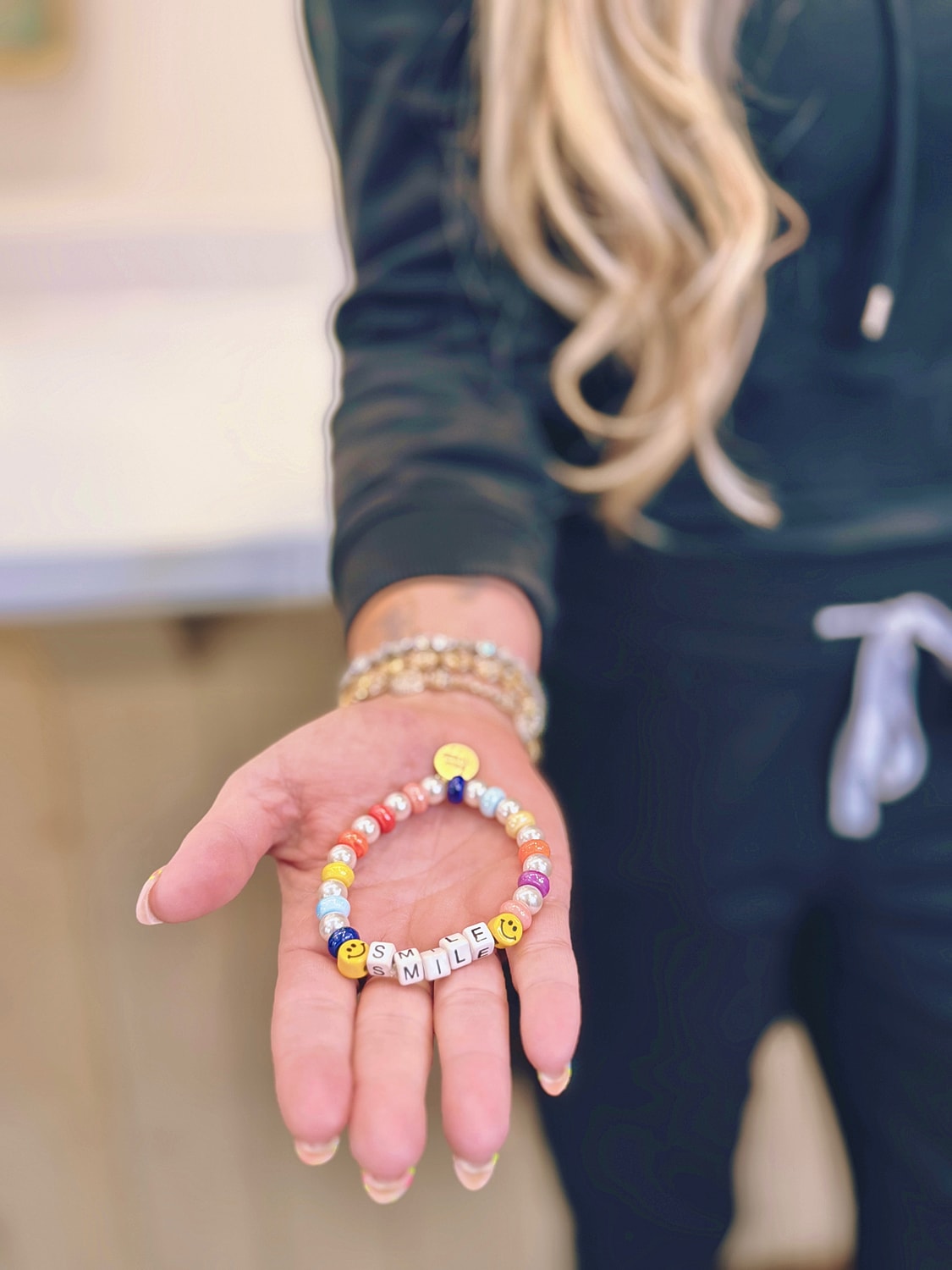 Colorful beaded bracelet spelling "SMILE" in hand.
