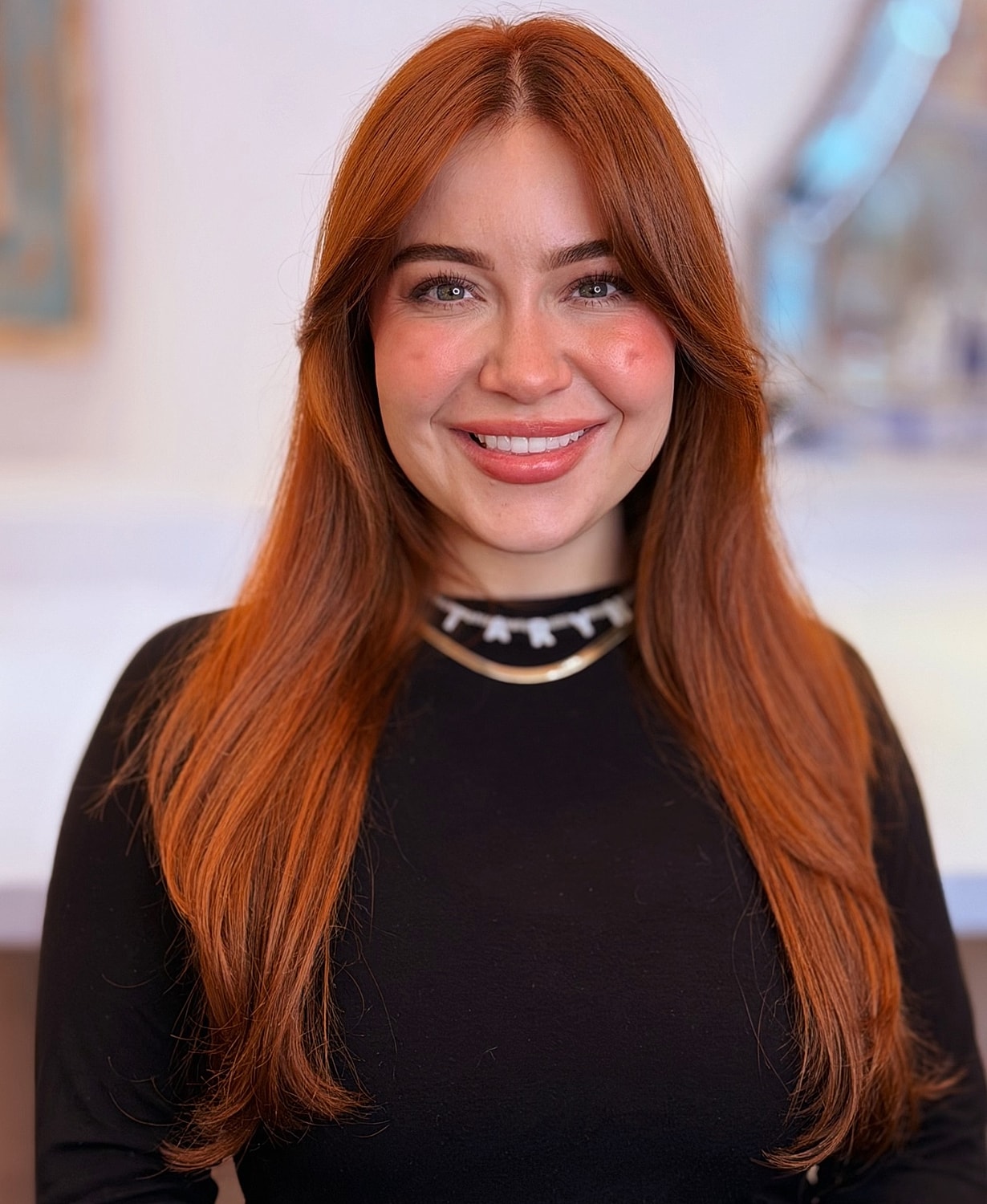 Smiling woman with long red hair in black top.