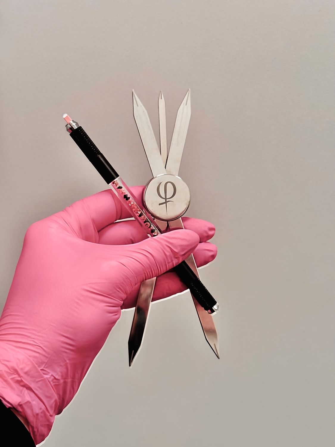 Hand holding drafting tools and pink glove.