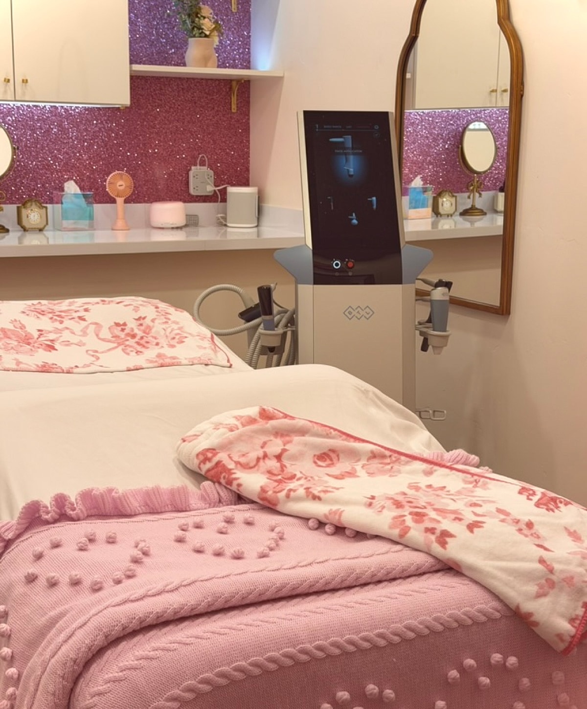 Beauty treatment room with pink decor and equipment.