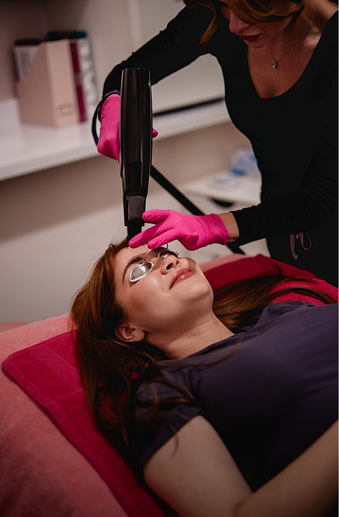 Woman receiving EMFACE facial treatment procedure.
