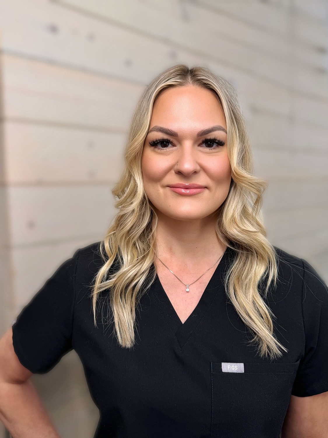 Smiling woman in scrubs with long blonde hair.