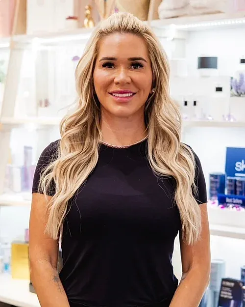 Smiling woman with long blonde hair in shop.