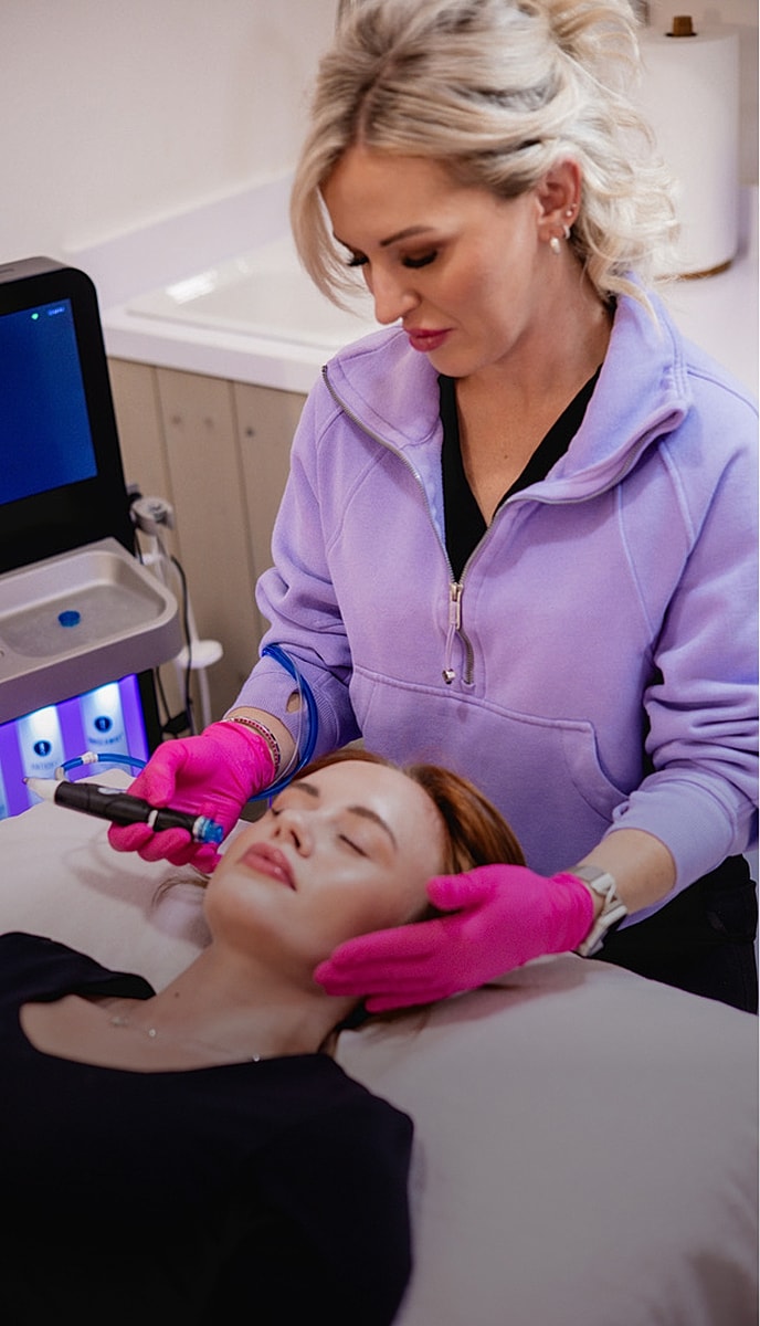 Woman beside Alma Harmony device in clinic.
